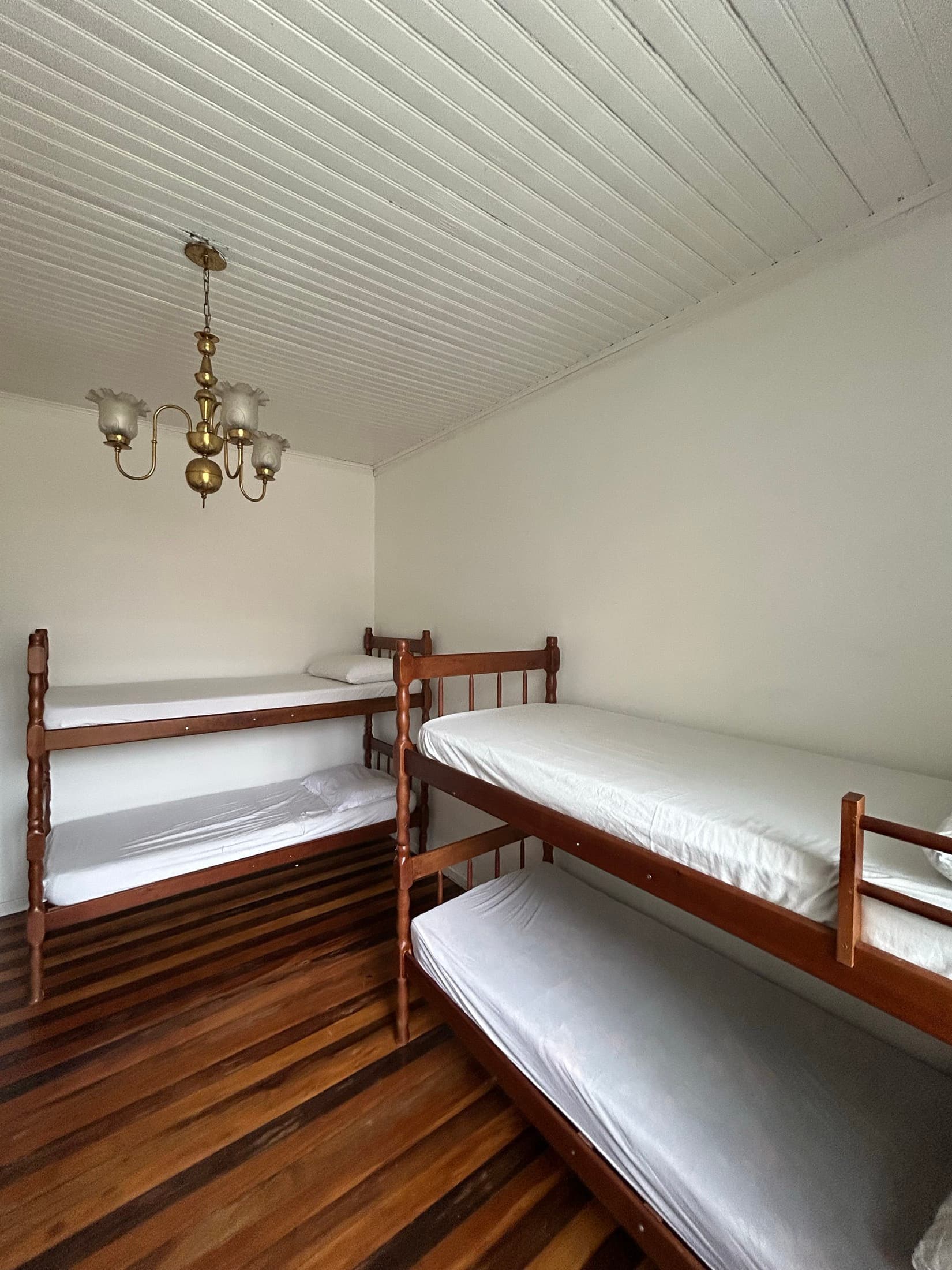 Dois beliches de madeira em quarto de paredes claras
